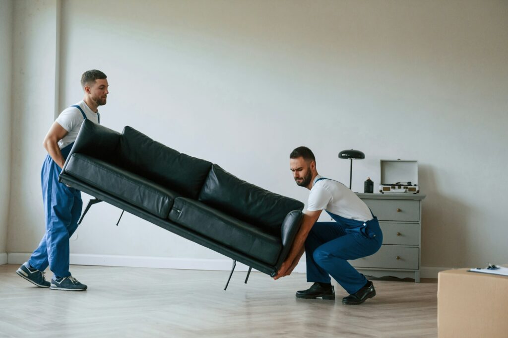 Why You Need High-Quality Moving and Packing Materials 2 Sofa in hands. Two moving service employees in a room